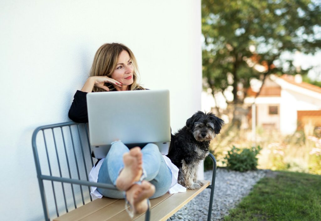 Frau mit Laptop und Hund draußen