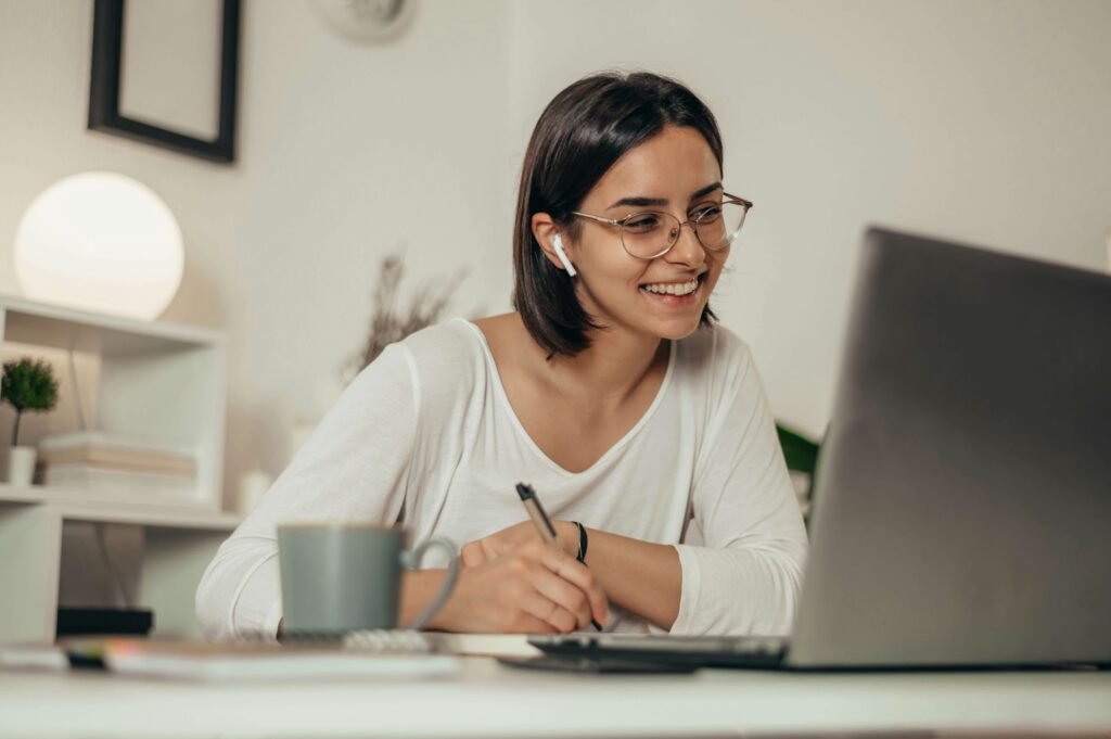 Frau sitzt am Tisch vor ihrem Laptop