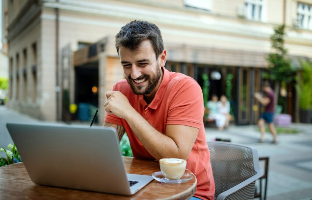 Mann mit Laptop und Cafe